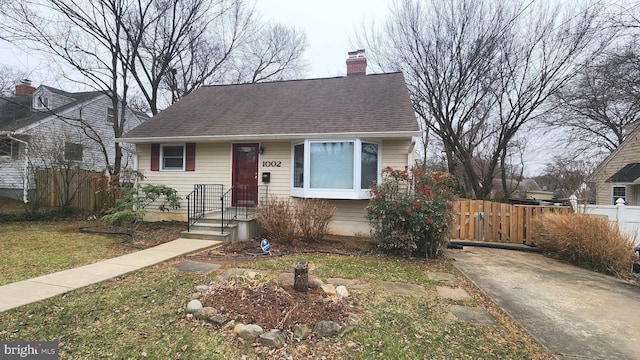 view of front of house with a chimney, fence, and roof with shingles