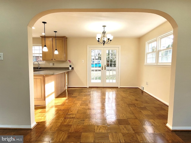 unfurnished dining area with baseboards, a sink, and a healthy amount of sunlight