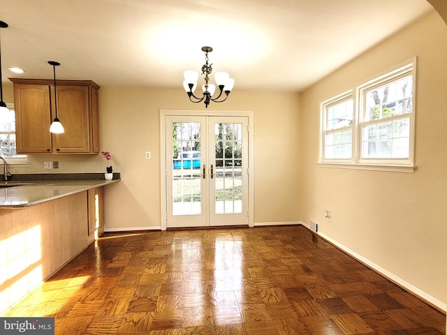 interior space with french doors, plenty of natural light, baseboards, and an inviting chandelier