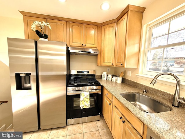 kitchen featuring light stone counters, light tile patterned floors, appliances with stainless steel finishes, a sink, and under cabinet range hood