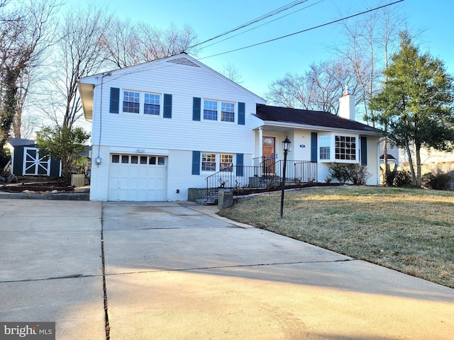 split level home with driveway, a chimney, an attached garage, a front yard, and brick siding