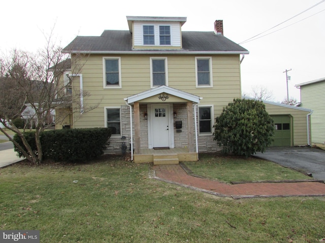 view of front facade with aphalt driveway, a chimney, an attached garage, a front yard, and stone siding