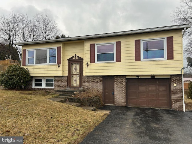 split foyer home with a garage, a front yard, aphalt driveway, and brick siding