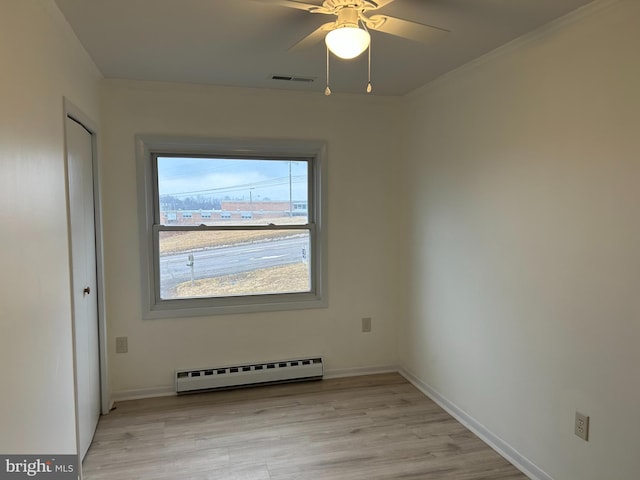 unfurnished room with light wood-style floors, visible vents, a baseboard heating unit, and baseboards