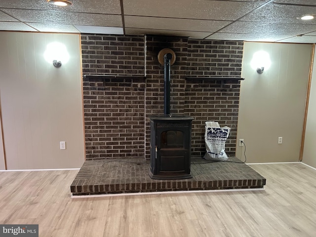 details featuring a drop ceiling, wood finished floors, and a wood stove