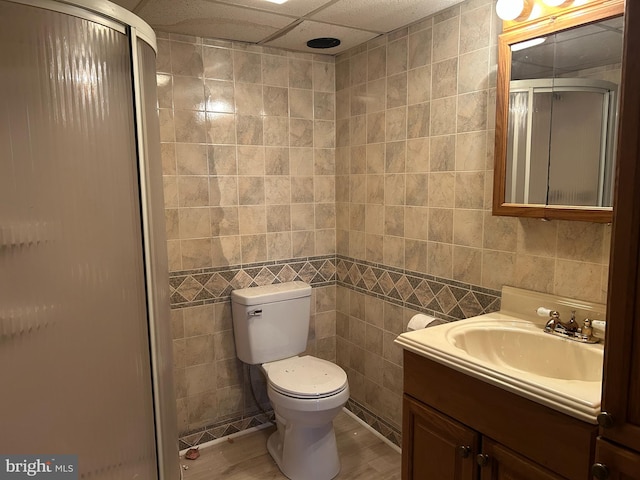 full bath featuring toilet, tile walls, a shower stall, and vanity