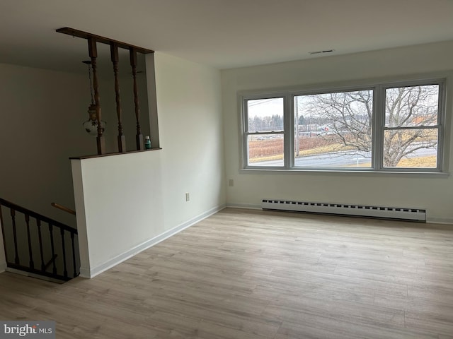 unfurnished room featuring a baseboard radiator, visible vents, baseboards, and wood finished floors