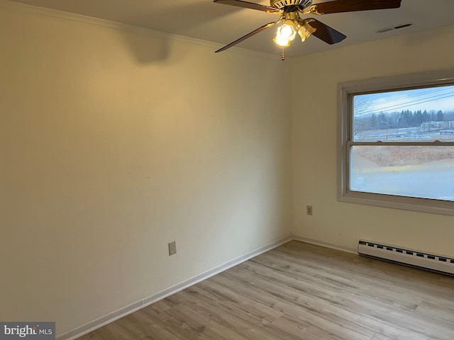 spare room with a baseboard radiator, visible vents, baseboards, light wood finished floors, and crown molding