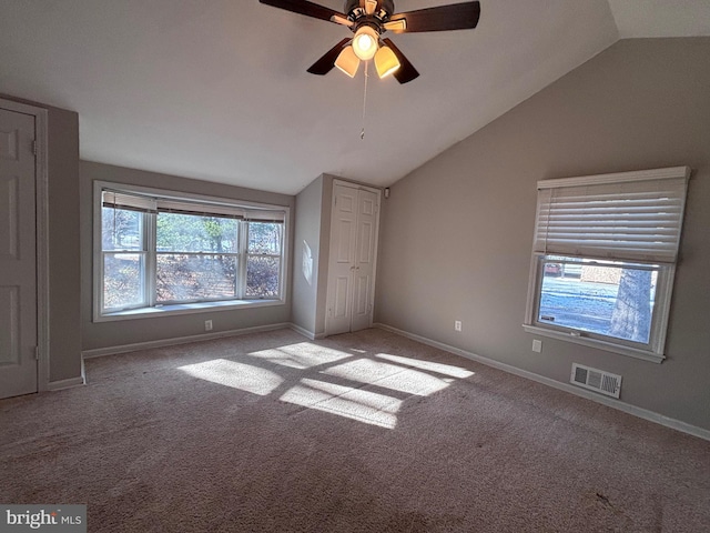 unfurnished bedroom with carpet floors, visible vents, vaulted ceiling, and baseboards