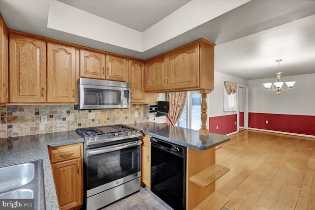 kitchen with stainless steel appliances, a peninsula, light wood finished floors, dark countertops, and tasteful backsplash