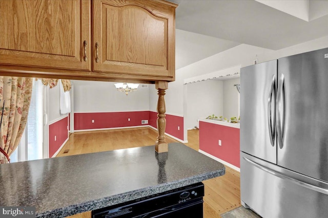 kitchen with light wood finished floors, baseboards, dark countertops, dishwashing machine, and freestanding refrigerator