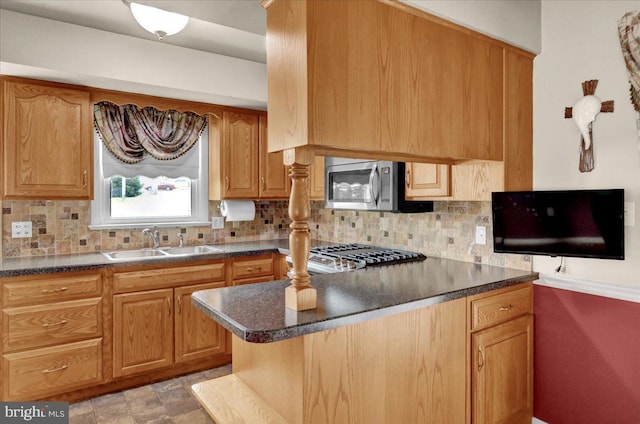 kitchen with stainless steel microwave, dark countertops, a sink, and decorative backsplash