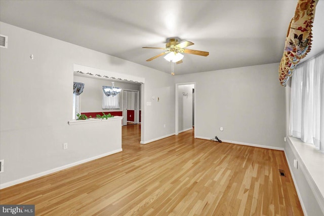 interior space with visible vents, baseboards, wood finished floors, and ceiling fan with notable chandelier