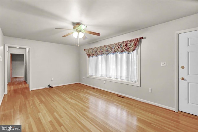 empty room with light wood-style floors, visible vents, baseboards, and a ceiling fan