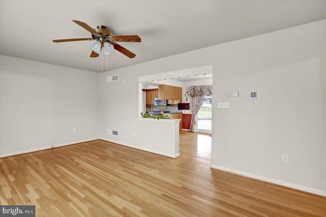 unfurnished living room featuring light wood finished floors, a ceiling fan, visible vents, and baseboards