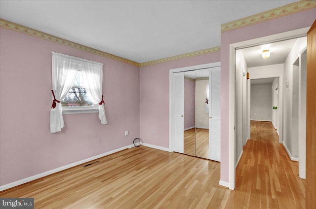 unfurnished bedroom with light wood-style floors, a closet, visible vents, and baseboards