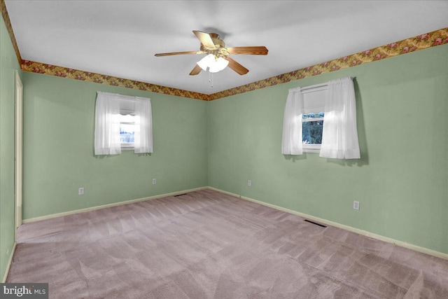 carpeted empty room with ceiling fan, visible vents, and baseboards