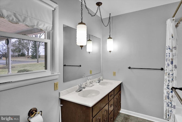 full bathroom with double vanity, a shower with shower curtain, a sink, and baseboards