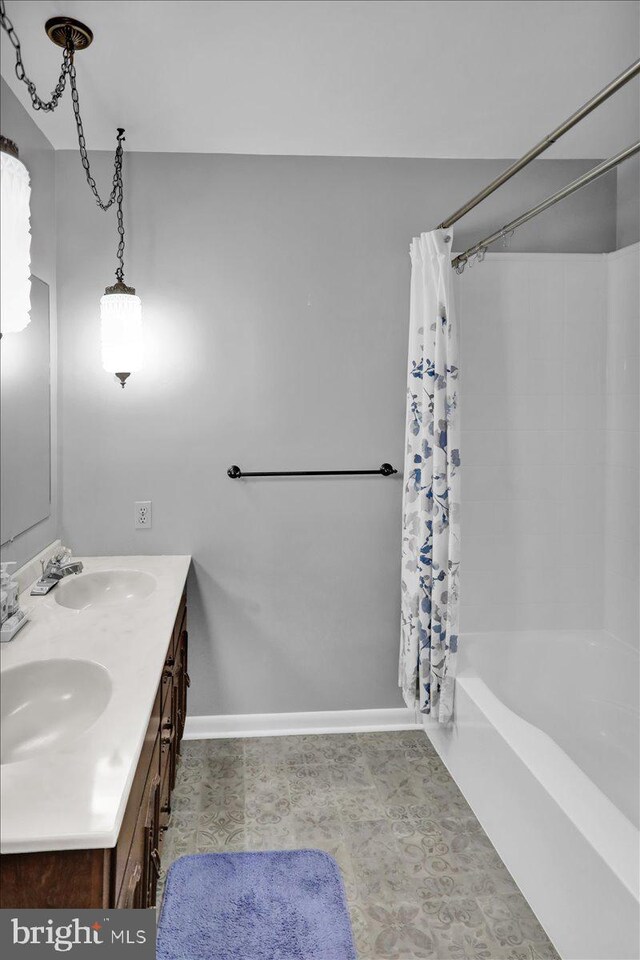 bathroom featuring shower / bath combo, a sink, baseboards, and double vanity