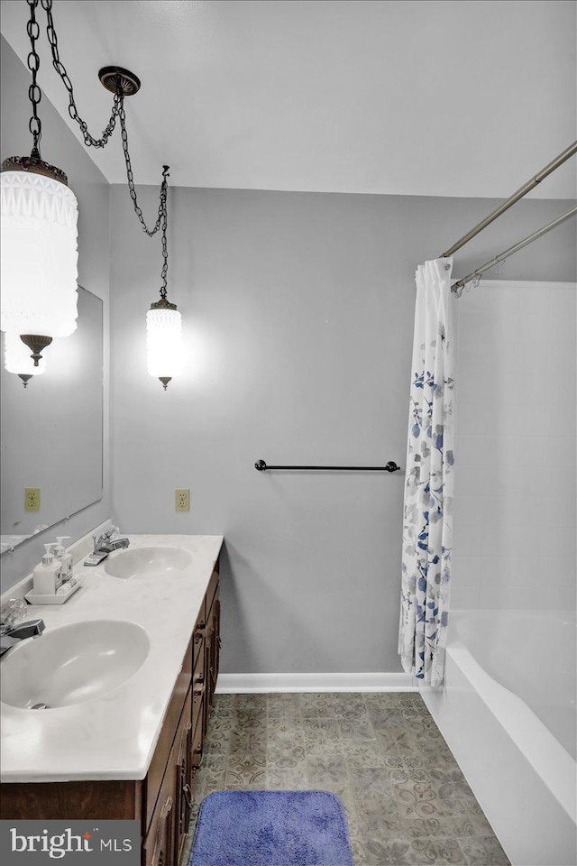 full bath featuring shower / bath combination with curtain, a sink, baseboards, and double vanity