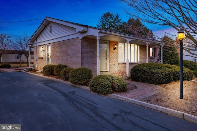 view of front of home featuring brick siding and a chimney