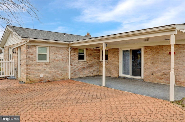 rear view of house featuring a shingled roof, a chimney, crawl space, a patio area, and brick siding