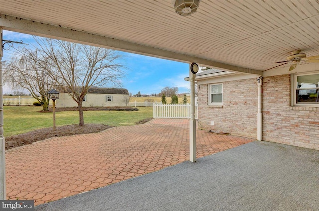 view of patio / terrace with an outbuilding, ceiling fan, driveway, and fence