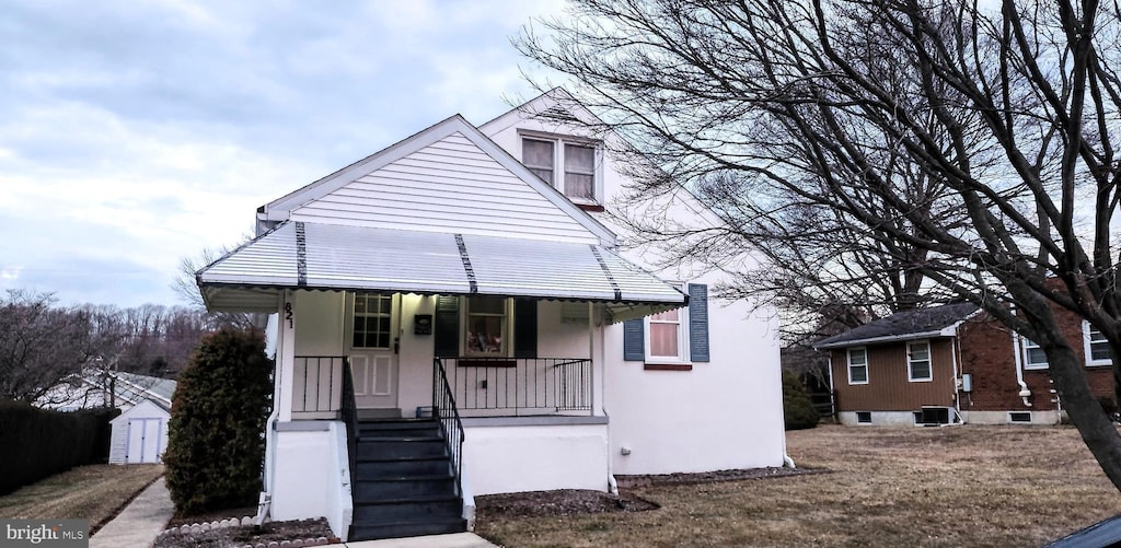 view of front of property featuring a porch, central AC, an outdoor structure, and stucco siding