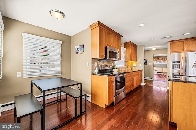 kitchen featuring visible vents, brown cabinetry, decorative backsplash, appliances with stainless steel finishes, and dark wood-type flooring