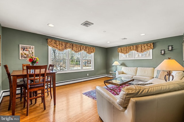 living area featuring a healthy amount of sunlight, baseboards, visible vents, and wood finished floors