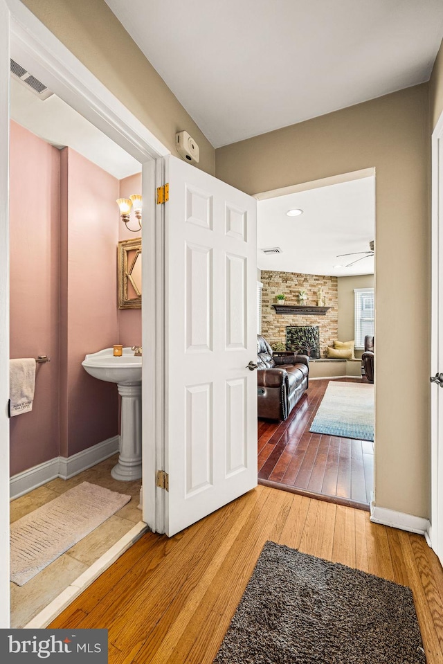 hall featuring baseboards, visible vents, and hardwood / wood-style floors