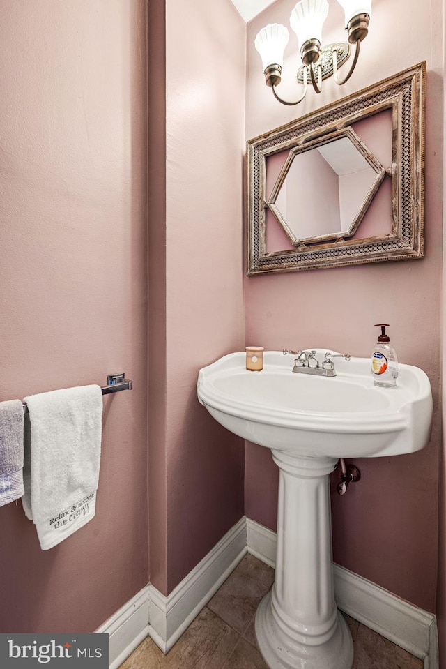 bathroom featuring baseboards, tile patterned flooring, and a notable chandelier