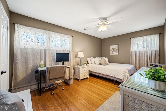 bedroom with ceiling fan, visible vents, and wood finished floors