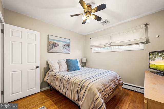 bedroom featuring visible vents, a baseboard heating unit, a ceiling fan, wood finished floors, and baseboards