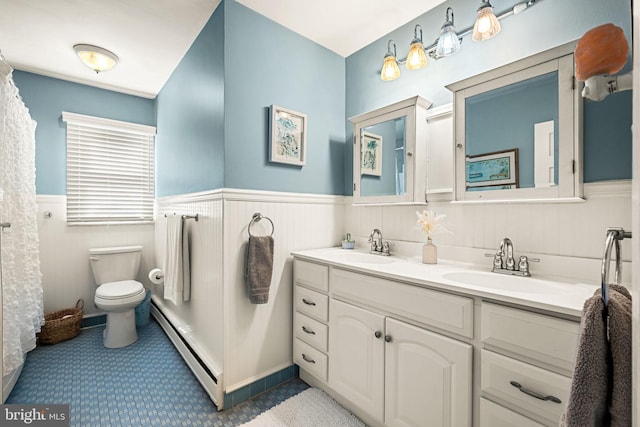 bathroom with a wainscoted wall, baseboard heating, a sink, and toilet