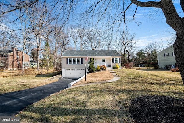 view of front of house featuring a garage, a chimney, aphalt driveway, and a front yard