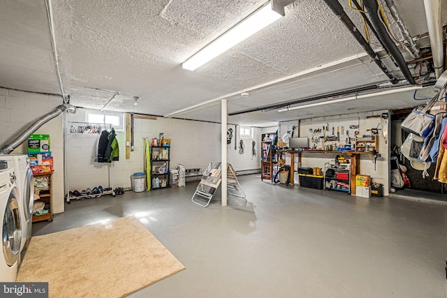 garage featuring concrete block wall, a baseboard radiator, and washer and clothes dryer