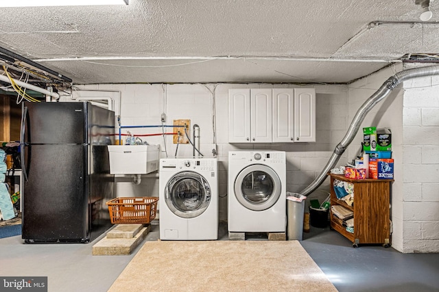 washroom with cabinet space, a sink, and washing machine and clothes dryer