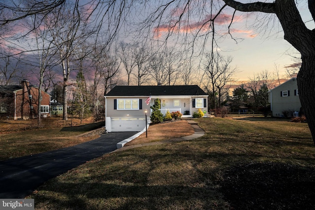 view of front facade featuring a garage, a chimney, a yard, and driveway