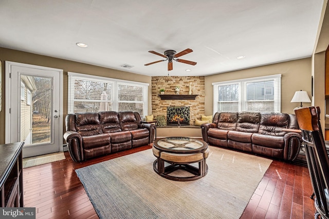 living room featuring dark wood-style flooring, a fireplace, visible vents, and recessed lighting