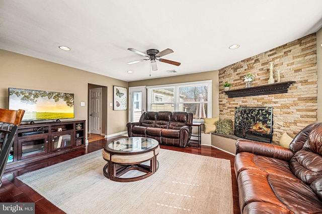 living area featuring a stone fireplace, recessed lighting, wood finished floors, a ceiling fan, and visible vents