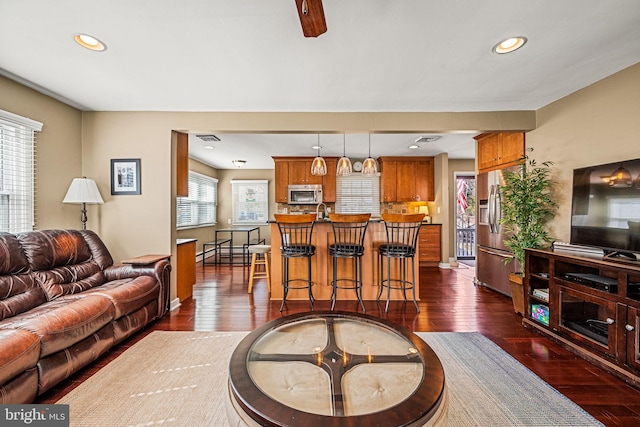 living area featuring baseboards, visible vents, dark wood-type flooring, a baseboard heating unit, and recessed lighting