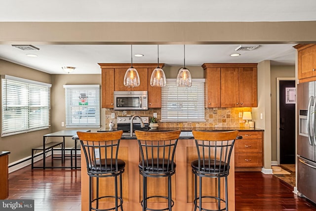 kitchen with a baseboard heating unit, appliances with stainless steel finishes, visible vents, and brown cabinets