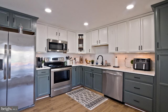 kitchen featuring stainless steel appliances, light countertops, a sink, and gray cabinetry