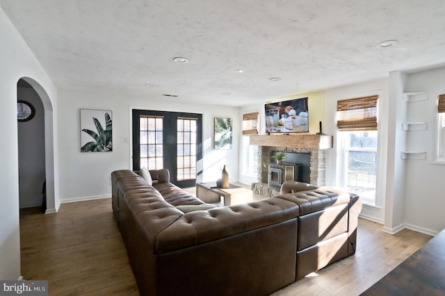 living area with a wealth of natural light, baseboards, arched walkways, and wood finished floors