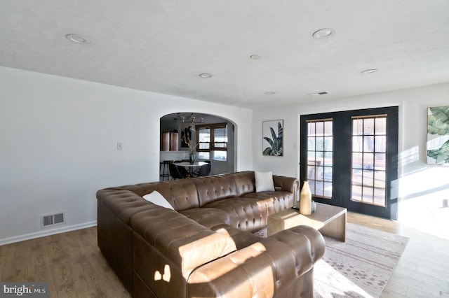 living area featuring arched walkways, french doors, visible vents, and wood finished floors