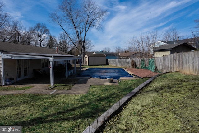 view of yard featuring a storage shed, a patio, a fenced backyard, an outbuilding, and french doors