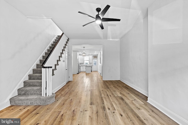 interior space with ceiling fan, stairway, light wood-type flooring, and baseboards