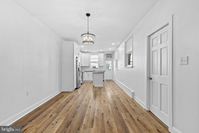 kitchen featuring a baseboard radiator, white cabinetry, stainless steel refrigerator with ice dispenser, backsplash, and an inviting chandelier