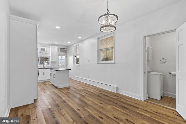 kitchen featuring a baseboard radiator, light wood-style floors, white cabinets, an AC wall unit, and dark countertops